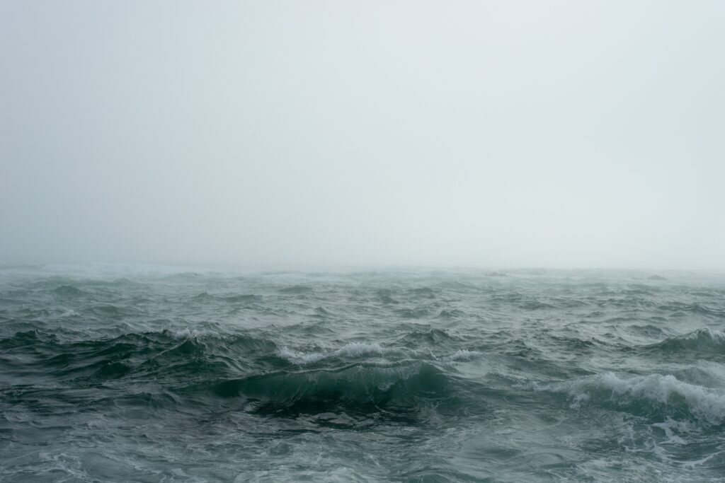 A gray, misty sky with choppy waves in the ocean.