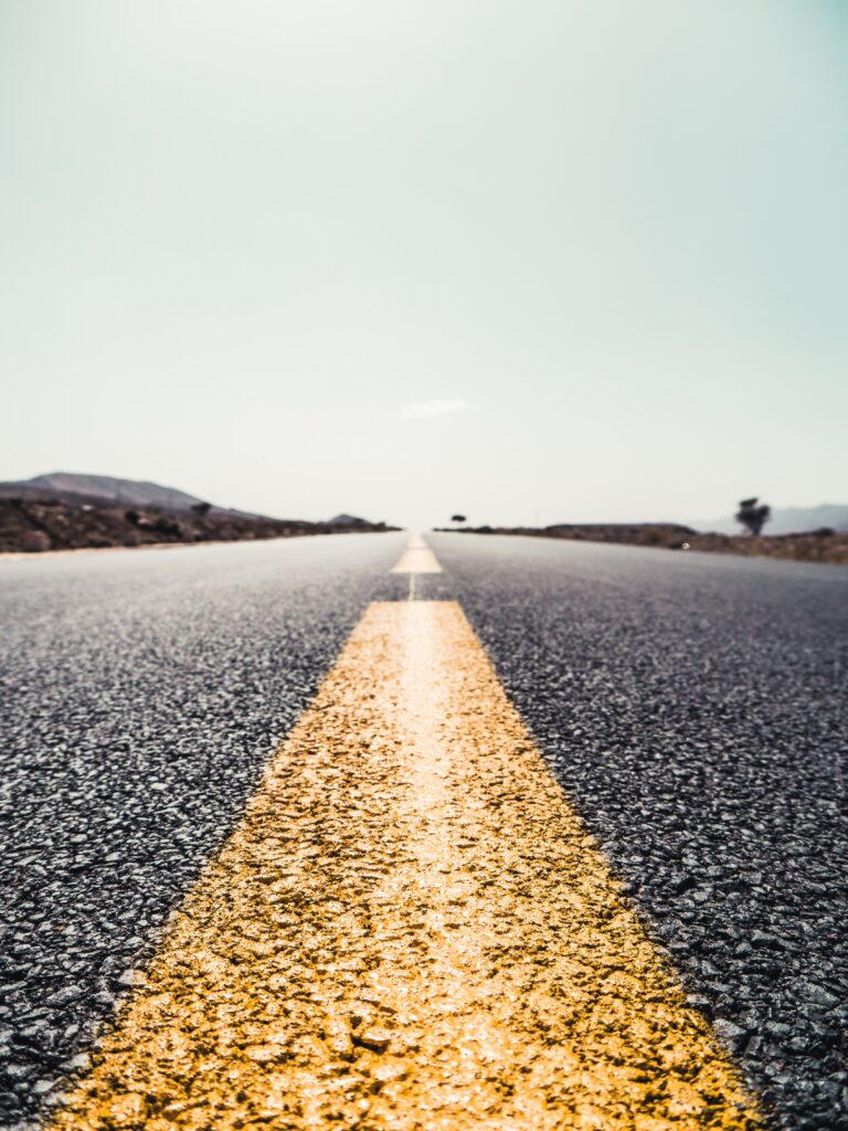 a close up picture of a road and the yellow markings on the road. Mountains are in the distance