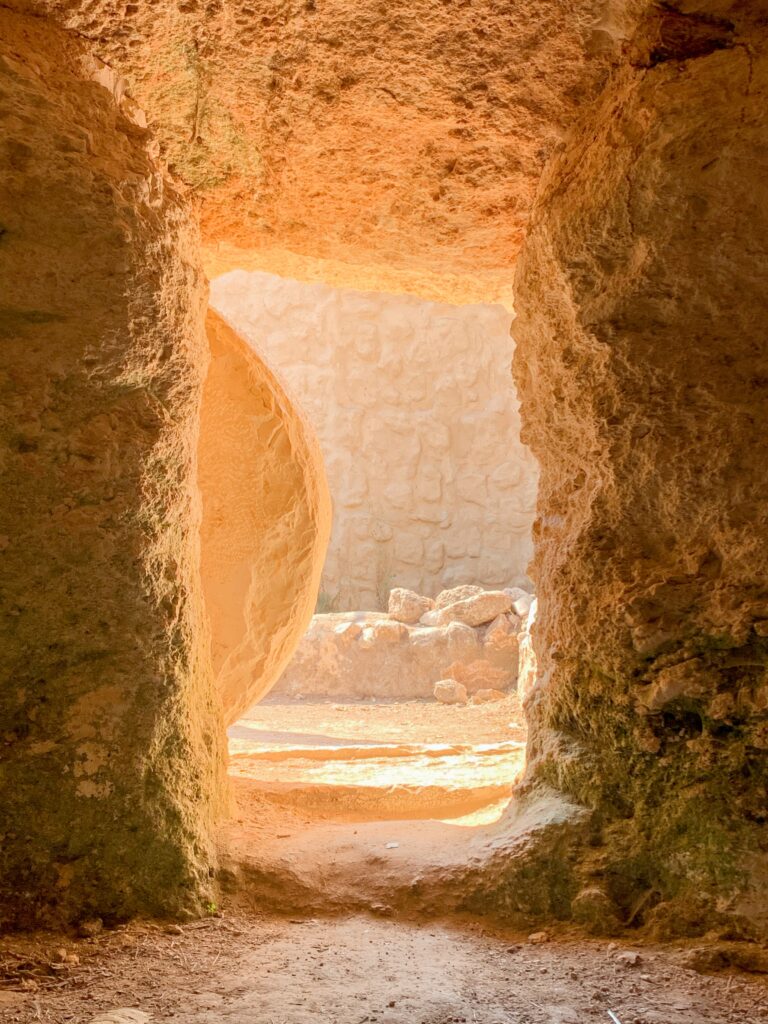 opening of a tomb. There is a stone that has been rolled away so you can see to the outside of the empty tomb.