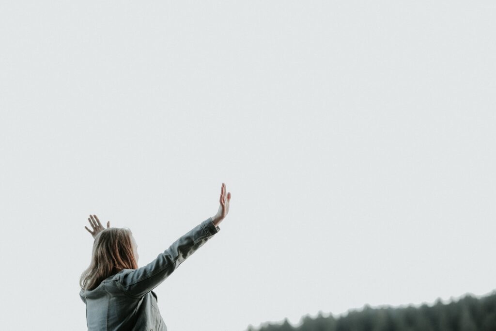 Woman with hands raised in a posture of worship. Worship is an act of waiting.